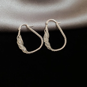 Macro shot of silver twisted rope water drop earrings on a premium satin background