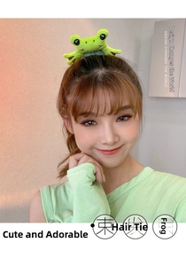 Detailed view of a green plush frog hair scrunchie worn on a messy bun hairstyle