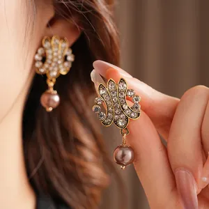 Vintage hollow gold earrings with sparkling crystals and a brown pearl pendant