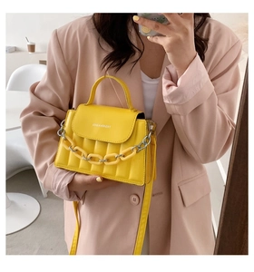 Detail of yellow crossbody bag with silver chain strap and vertical stitched texture