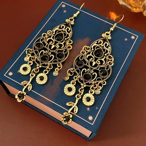 Macro detail of vintage gold earrings with black stones and hollowed-out flower design