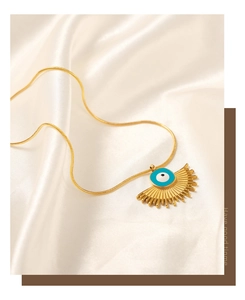 Macro shot of gold evil eye fan pendant on a snake chain over soft silk fabric