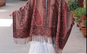 Dettaglio di scialle rosso con motivo paisley frange etniche e morbido tessuto a trama