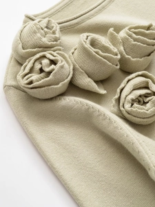 Dettaglio macro di fiori in maglia fatti a mano su un maglione verde chiaro
