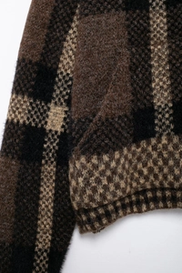 Detail of checkered knit bomber jacket showing brown and black plaid wool texture