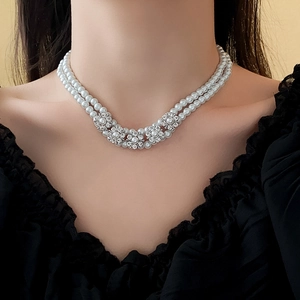 Close-up of double-layer pearl necklace with three diamond-encrusted flower charms on model