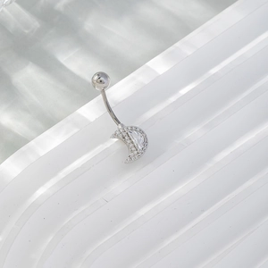 Silver crescent moon belly button ring with sparkling crystals on a textured background