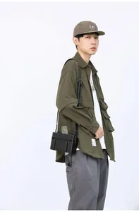 Dettaglio borsa a tracolla nera con cuciture bianche su outfit in stile utility