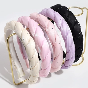 Braided fabric headbands with rhinestones in five pastel colors on a gold display stand