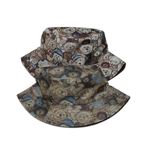 Detailed view of jacquard bear patterns on two stacked sun hats in brown and dark tones