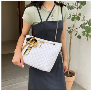 Detail of white quilted crossbody bag with golden deer charm and silk scarf on model