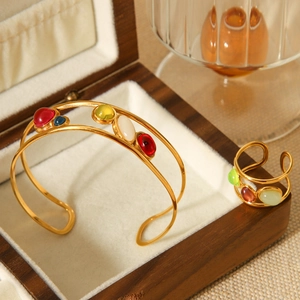 Detail of vintage gold bangle and ring set with multicolored natural stones in a wooden box