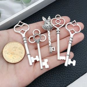 Five vintage silver metal key charms with rabbit head design and a size reference coin