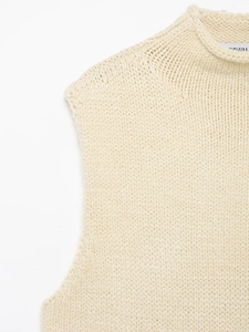 Macro shot of off-white chunky knit texture on the neckline and shoulder of the vest