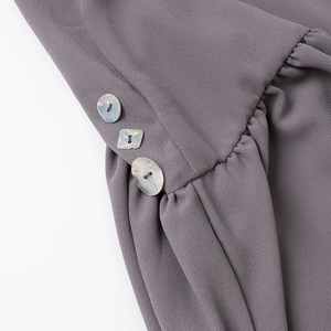 Dettaglio del tessuto in chiffon grigio-viola con pieghe e bottoni decorativi effetto marmo