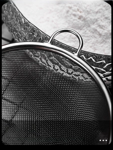 Detailed macro view of the fine stainless steel mesh strainer with durable side hooks