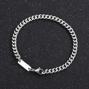 Gros plan d'un bracelet gourmette argenté avec plaque carrée sur fond noir texturé