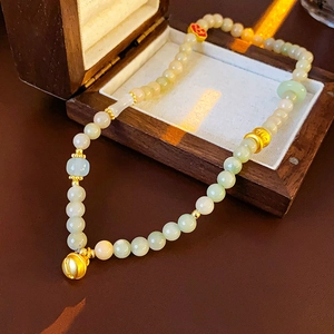 Detail of jade bead bracelet featuring golden auspicious cloud charm and bell pendant