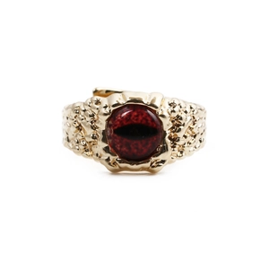 Detailed view of the gold dragon eye ring with a red gemstone and hammered metal texture