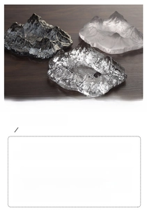 Detailed view of three glacier-shaped ice pattern glass ashtrays on a dark wood surface