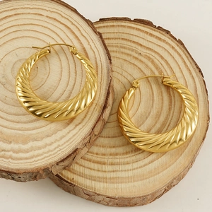 Grandi orecchini a cerchio dorati a spirale su fette di legno naturale
