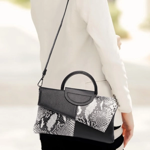 Chic black and white snakeskin pattern handbag shown being held by a model outdoors