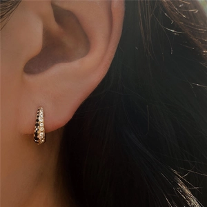 Close-up of S925 silver huggie earring with black and white zircon crystals on a model