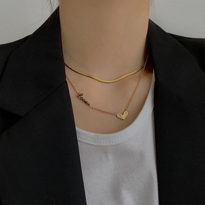 Double-layered gold titanium necklace with heart and Love pendant on a model in a suit