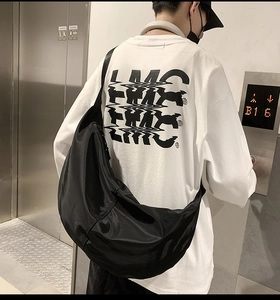 Rear view of a model wearing the black nylon crossbody dumpling bag in a casual setting