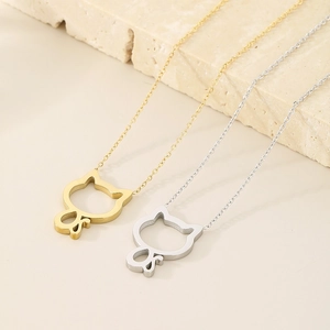 Close-up of hollow cat pendants in gold and silver finishes on elegant stone surface