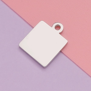 Detailed macro view of a polished square stainless steel pendant on a pink and purple backdrop