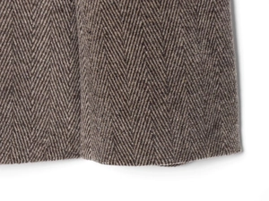 Macro shot of brown herringbone wool fabric showing detailed weave texture on the blazer