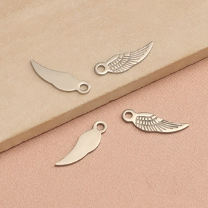 Vue détaillée de quatre breloques ailes en argent aux finitions polies et texturées