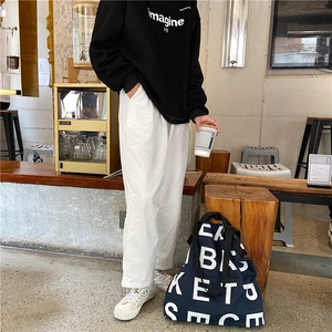 Deep blue canvas tote bag with letter print shown in a casual cafe setting outfit