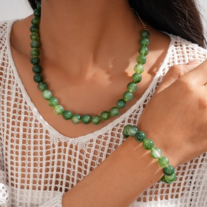 Detail of green acrylic beaded necklace and bracelet set worn on a model's neck and wrist