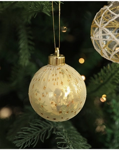Detail of 6cm gold mesh and transparent glitter Christmas balls on a warm festive tree
