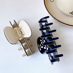 Large acetate hair claws in beige and navy with delicate black line detail and flower motif