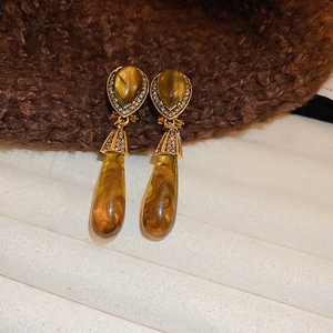 Dettaglio macro di orecchini d'oro retrò con gocce di resina ambra e cristalli lucidi