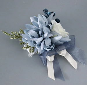 Gros plan d'une boutonnière élégante avec dahlia bleu-gris, rose blanche et rubans fins