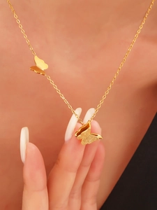 Close-up of golden stainless steel necklace with polished and frosted butterfly charms