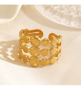 Dettaglio anello placcato oro con tre dischi tondi su elegante seta beige