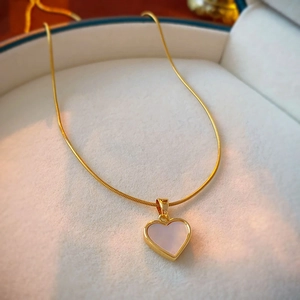 Detailed view of heart-shaped shell pendant on golden snake chain necklace