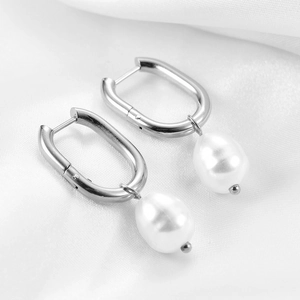 U-shaped stainless steel earrings with white drop pearls on white silk background