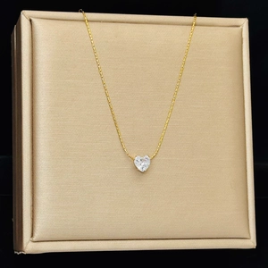 Detailed view of a gold titanium necklace featuring a heart-shaped diamond pendant on a display