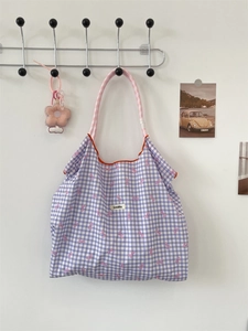 Detail of purple gingham tote bag with pink bow prints and brand woven label