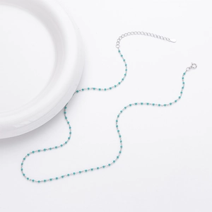 Detail of s925 sterling silver necklace with small turquoise beads on white background