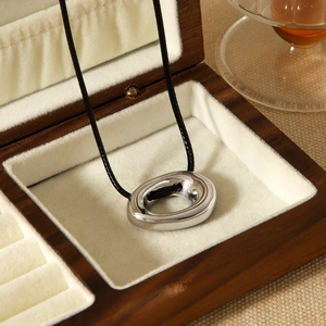 Irregular hollow oval stainless steel pendant necklace on black woven cord in wooden box