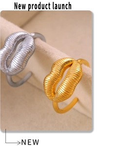 Close-up of gold and silver lip-shaped rings with textured finish on velvet stand
