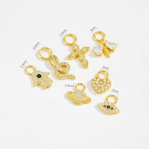 Close-up of seven assorted 925 silver gold-plated charms with cubic zirconia stones
