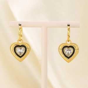 Close-up of gold heart earrings with black enamel and heart-shaped cubic zirconia stone